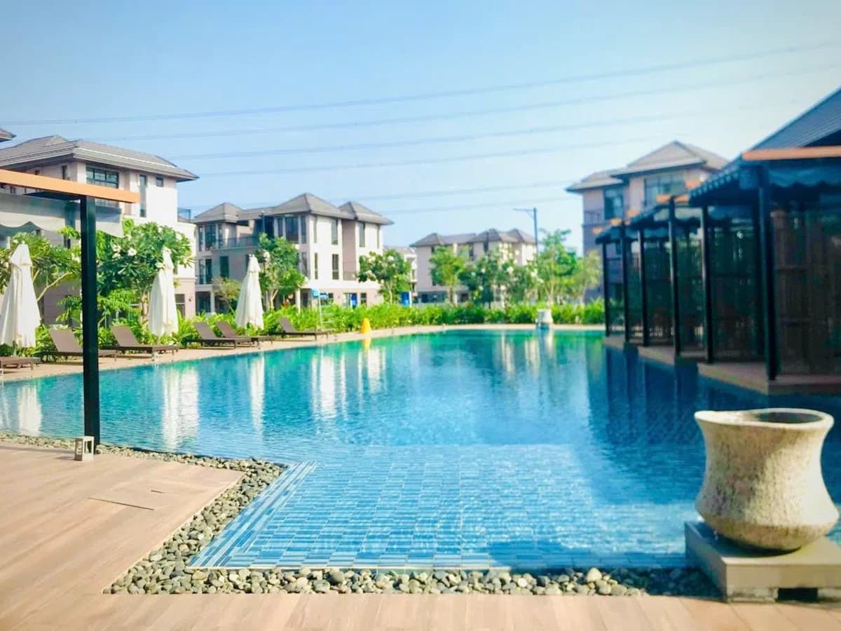 Hồ bơi ngoài trời clubhouse với ghế tắm nắng và cabana tại khu đô thị Zeitgeist Nhà Bè
