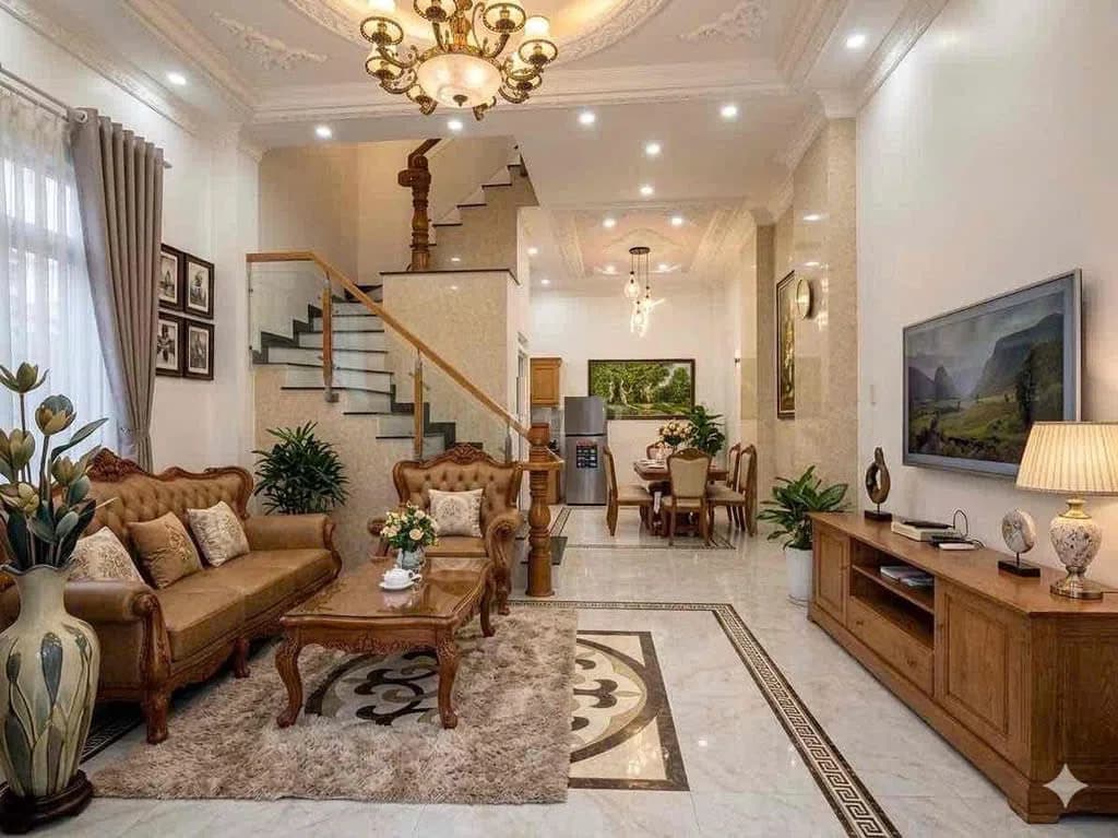 Phòng khách với bộ sofa, kệ tivi gỗ và cầu thang lên lầu, phía sau là khu bàn ăn