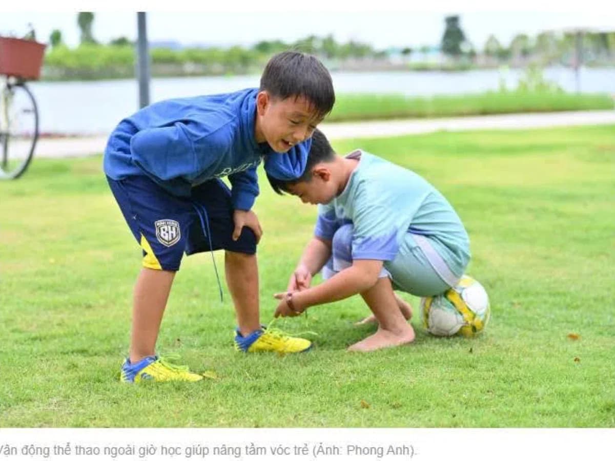 Hai bé trai chơi bóng trên bãi cỏ xanh trong khu đô thị