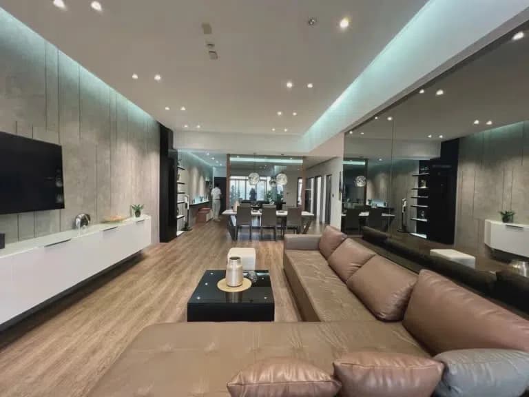 Phòng khách rộng với sofa da, kệ tivi và khu bàn ăn phía sau